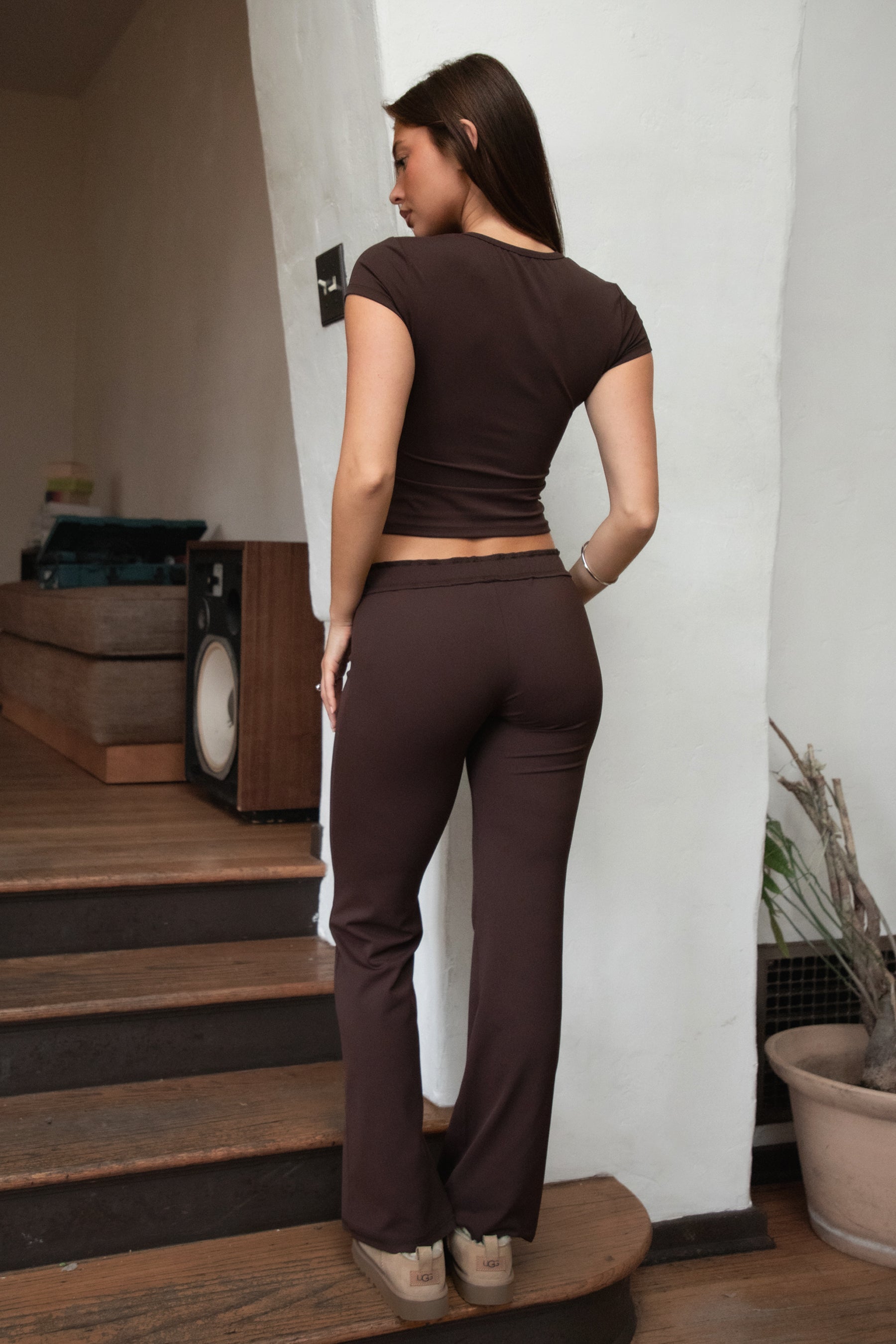 Woman wearing TIC TOC PH31905BA-NYLEE-WL navy NYLEE WL wide leg pants made from soft span jersey fabric, featuring a high-stretch body-hugging fit through the hips, foldover waistband with tie detail, and full-length wide leg silhouette, styled indoors with a matching top for a coordinated lounge/athleisure look.