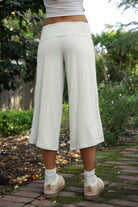 Woman wearing TIC TOC PH32000 SORA rayon spandex fold over low rise wide leg leggings featuring a soft lightweight jersey fabric, fold-over waistband, relaxed wide leg silhouette, and capri length, styled for a clean laid-back lounge and everyday look.