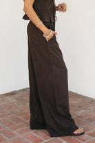 Woman wearing SOLSTICE viscose linen drawstring wide leg pants featuring a relaxed flowy silhouette, elastic waistband with adjustable drawstring, functional side pockets, back patch pockets, and lightweight breathable viscose linen fabric for effortless resort styling.