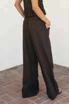 Woman wearing SOLSTICE viscose linen drawstring wide leg pants featuring a relaxed flowy silhouette, elastic waistband with adjustable drawstring, functional side pockets, back patch pockets, and lightweight breathable viscose linen fabric for effortless resort styling.