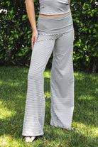 Woman wearing SAYLOR stripe stretch fold over wide leg pants featuring a fold over waistband, mid rise fit, wide leg relaxed silhouette, stripe jersey fabric, and lightweight stretch construction for soft comfortable lounge and casual styling.