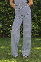 Woman wearing SAYLOR stripe stretch fold over wide leg pants featuring a fold over waistband, mid rise fit, wide leg relaxed silhouette, stripe jersey fabric, and lightweight stretch construction for soft comfortable lounge and casual styling.