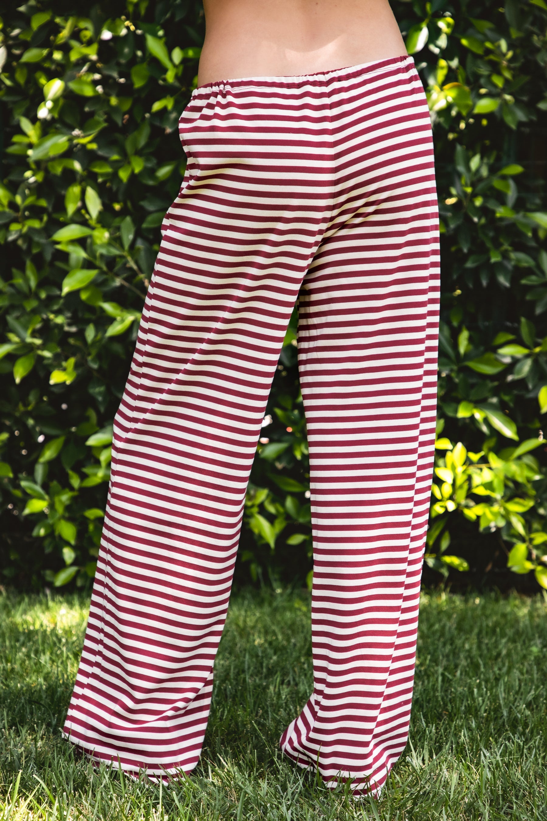 Woman wearing MARLOWE stretch mid waist stripe wide leg pants featuring an allover stripe pattern, adjustable drawstring waist, relaxed wide leg silhouette, full length fit, and soft stretch jersey fabric for cozy casual lounge styling.