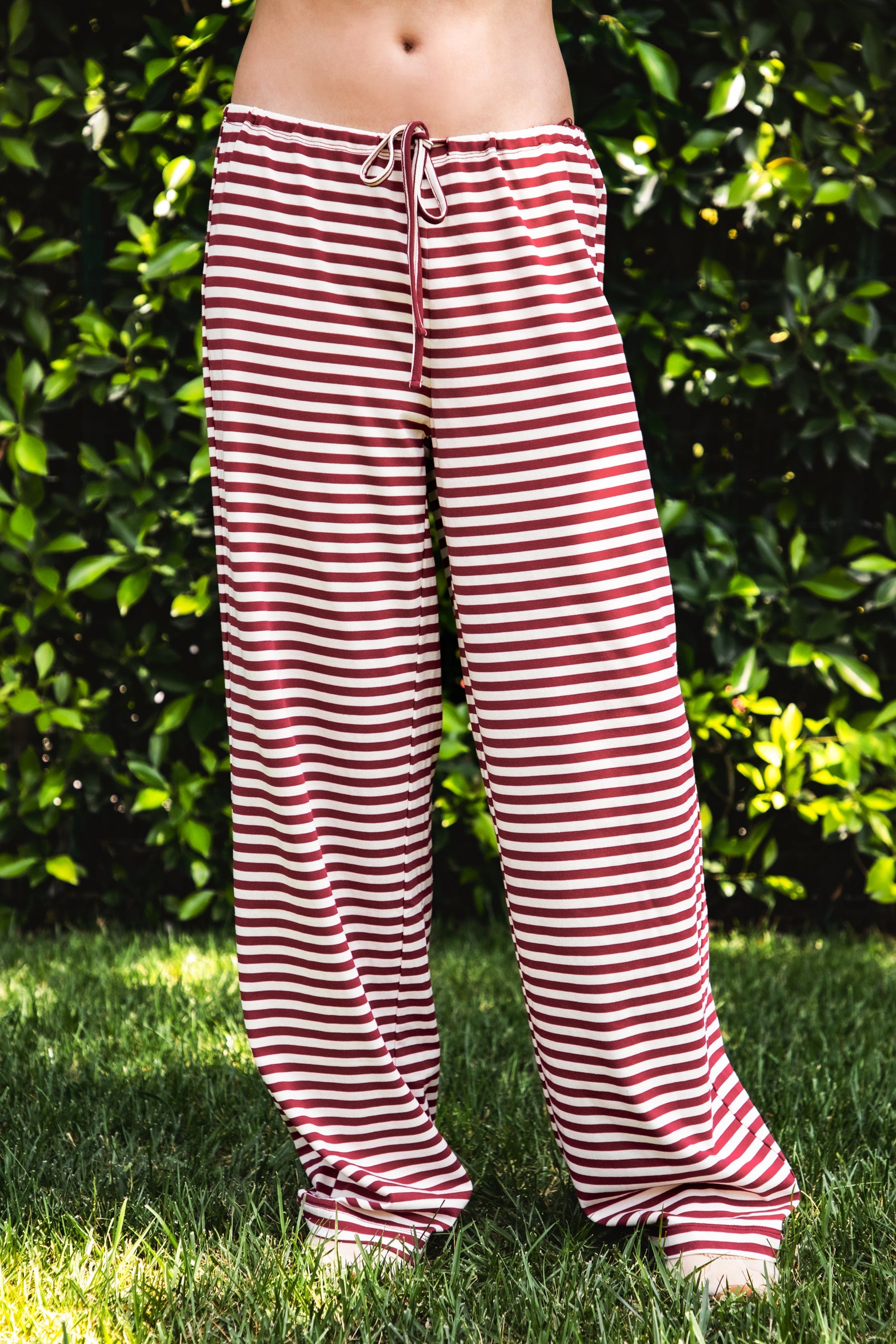 Woman wearing MARLOWE stretch mid waist stripe wide leg pants featuring an allover stripe pattern, adjustable drawstring waist, relaxed wide leg silhouette, full length fit, and soft stretch jersey fabric for cozy casual lounge styling.