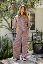 Woman wearing MARLOWE stretch mid waist stripe wide leg pants featuring an allover stripe pattern, adjustable drawstring waist, relaxed wide leg silhouette, full length fit, and soft stretch jersey fabric for cozy casual lounge styling.