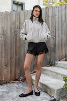 Woman wearing LUNETTE scalloped eyelash lace trim satin shorts featuring soft stretch satin fabric, high rise waist, clean tailored finish, delicate scalloped eyelash lace trim along the hem, hidden back zipper closure, and fully lined interior for added comfort and coverage.
