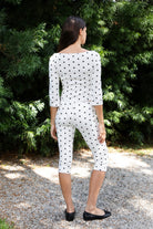 Woman wearing MARIE polka dot capri pants featuring soft cotton stretch jersey fabric, allover polka dot print, mid rise waist, clean pull on design, slim fitted silhouette through the hip and leg, cropped capri length, and delicate picot trim along the waistband designed to pair with the matching MARIE top.