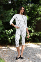 Woman wearing MARIE polka dot capri pants featuring soft cotton stretch jersey fabric, allover polka dot print, mid rise waist, clean pull on design, slim fitted silhouette through the hip and leg, cropped capri length, and delicate picot trim along the waistband designed to pair with the matching MARIE top.