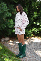 Woman wearing PIPPA polka dot plush fleece shorts featuring soft cotton blend fleece fabric, playful polka dot print, comfortable elastic waistband, easy pull on design, relaxed fit through the hips and legs, functional side pockets, short length, and clean finished hems designed to pair with the matching PIPPA sweatshirt.