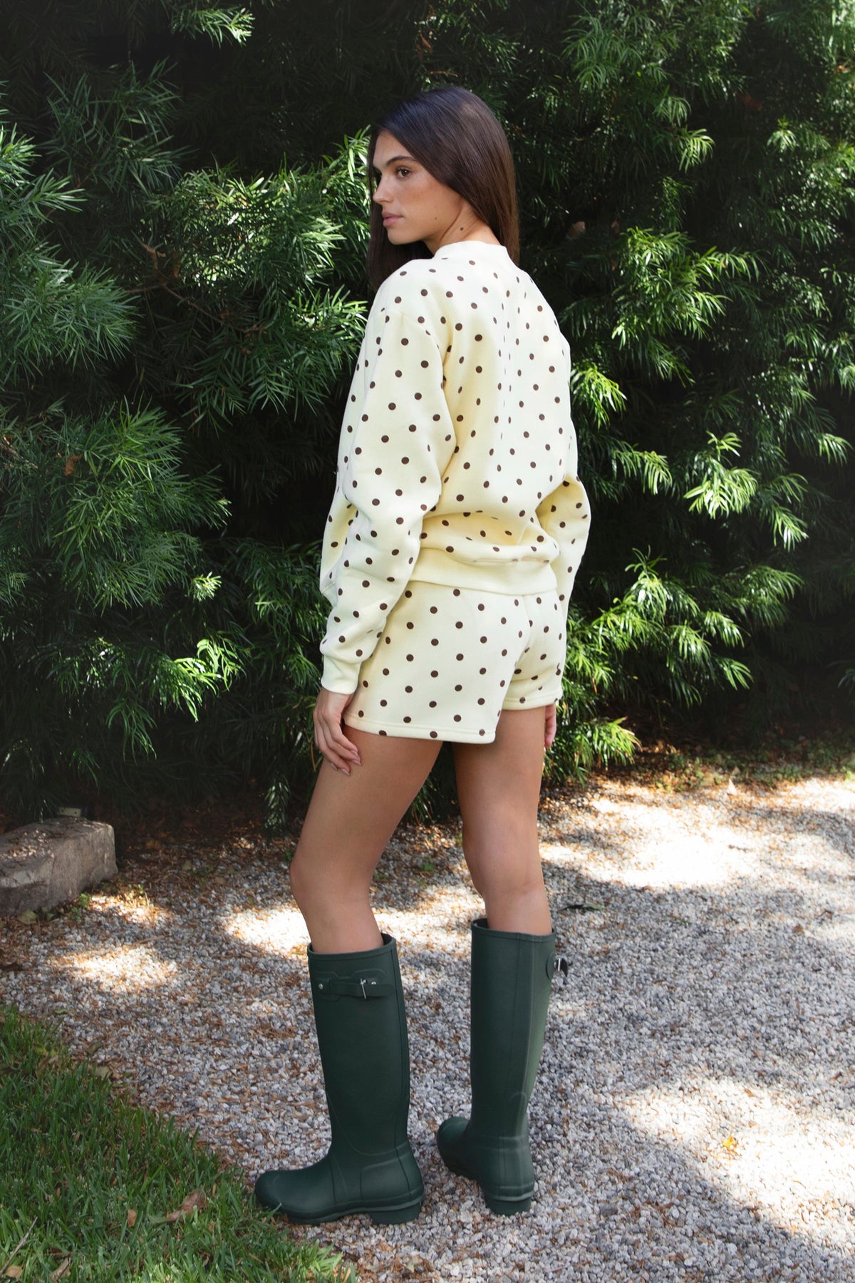 Woman wearing PIPPA polka dot plush fleece shorts featuring soft cotton blend fleece fabric, playful polka dot print, comfortable elastic waistband, easy pull on design, relaxed fit through the hips and legs, functional side pockets, short length, and clean finished hems designed to pair with the matching PIPPA sweatshirt.