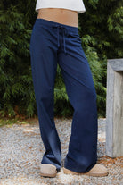 Woman wearing NAVYN waist band cotton wide leg pants featuring soft 100 percent cotton fabric, low rise waistline, relaxed fit, elastic waistband with adjustable drawstring tie, relaxed silhouette through the hips and thighs, wide leg design, full length cut, and straight hem for easy everyday styling.