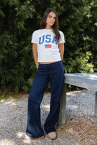 Woman wearing NAVYN waist band cotton wide leg pants featuring soft 100 percent cotton fabric, low rise waistline, relaxed fit, elastic waistband with adjustable drawstring tie, relaxed silhouette through the hips and thighs, wide leg design, full length cut, and straight hem for easy everyday styling.