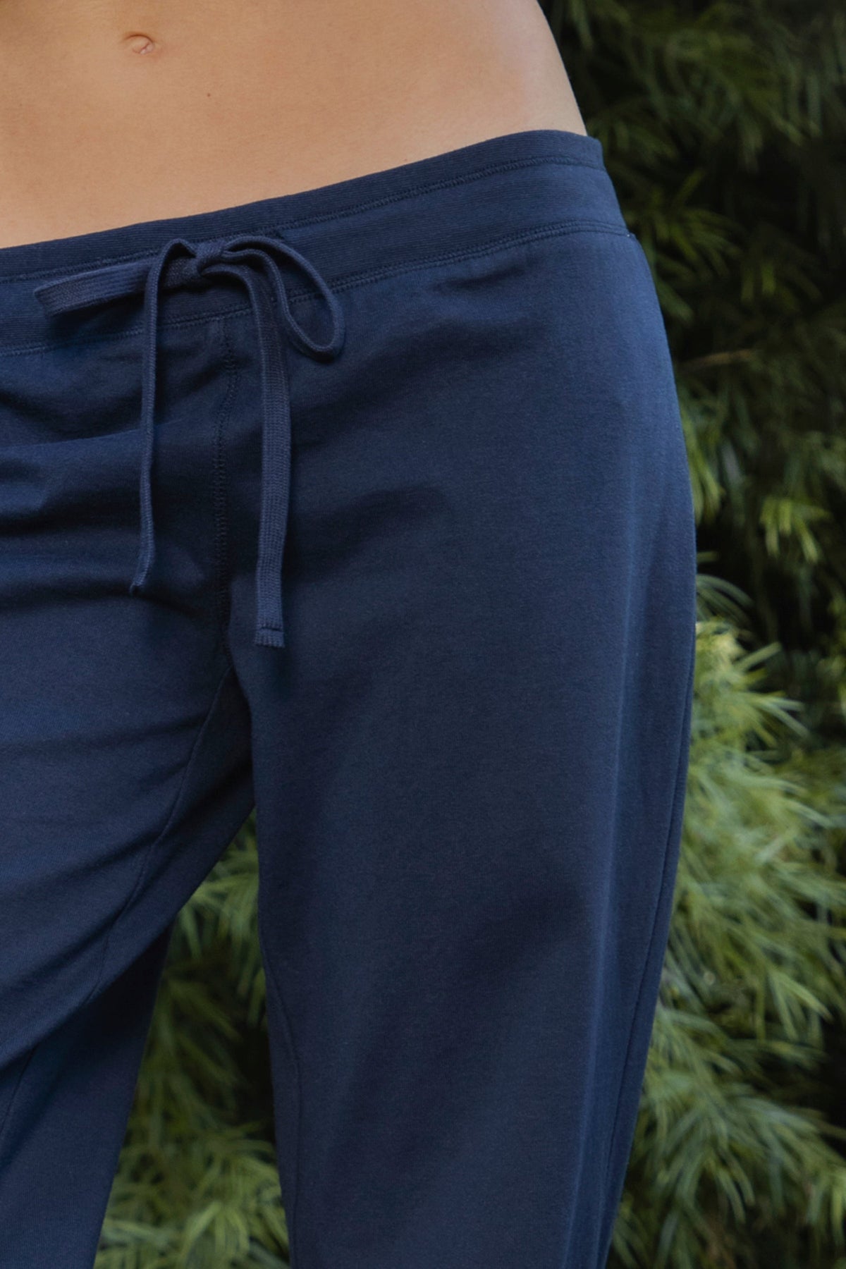 Woman wearing NAVYN waist band cotton wide leg pants featuring soft 100 percent cotton fabric, low rise waistline, relaxed fit, elastic waistband with adjustable drawstring tie, relaxed silhouette through the hips and thighs, wide leg design, full length cut, and straight hem for easy everyday styling.
