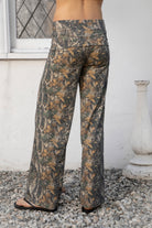 Woman wearing BAYOU dark woodland camo stretch foldover wide leg leggings featuring soft brushed stretch jersey fabric, allover woodland camo print, adjustable foldover waistband, relaxed wide leg silhouette, and four way stretch fabric designed for everyday comfort and easy movement.