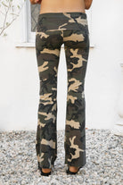 Woman wearing REMI dark military camo fold over flare leggings featuring soft stretch cotton jersey fabric, allover classic military camouflage print, low rise fit, wide fold over waistband, fitted hips and thighs, flared leg, garment washed finish, and full length pull on silhouette.