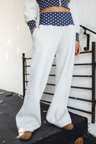 Woman wearing COSETTE polka dot waist wide leg sweatpants featuring soft fleece fabric, relaxed wide leg silhouette, contrast navy ribbed waistband with allover white polka dot pattern, high rise statement fit, soft heather grey body, full length design, functional side pockets, and matching set styling.