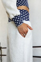 Woman wearing COSETTE polka dot waist wide leg sweatpants featuring soft fleece fabric, relaxed wide leg silhouette, contrast navy ribbed waistband with allover white polka dot pattern, high rise statement fit, soft heather grey body, full length design, functional side pockets, and matching set styling.