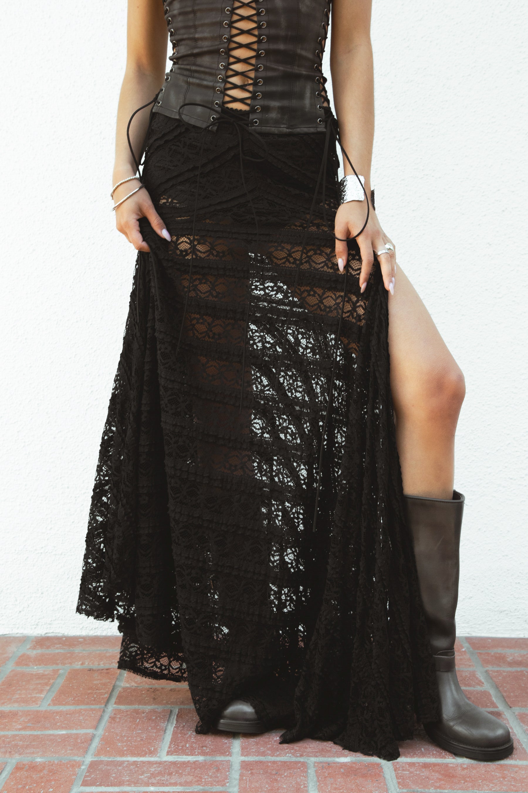 Woman wearing MARISS stretch lace side slit long skirt featuring sheer stretch lace fabric, flowy silhouette with airy movement, high side slit, picot trim waistband, and built-in micro shorts lining for coverage and comfort.