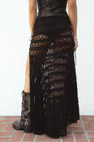 Woman wearing MARISS stretch lace side slit long skirt featuring sheer stretch lace fabric, flowy silhouette with airy movement, high side slit, picot trim waistband, and built-in micro shorts lining for coverage and comfort.