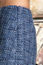 Woman wearing COCO navy blue lurex tweed skort featuring shimmering textured tweed fabric, subtle metallic lurex detail, mini length, skirt inspired front with hidden shorts comfort, clean fitted waist, side zipper closure, and fully lined construction for going out and holiday styling.