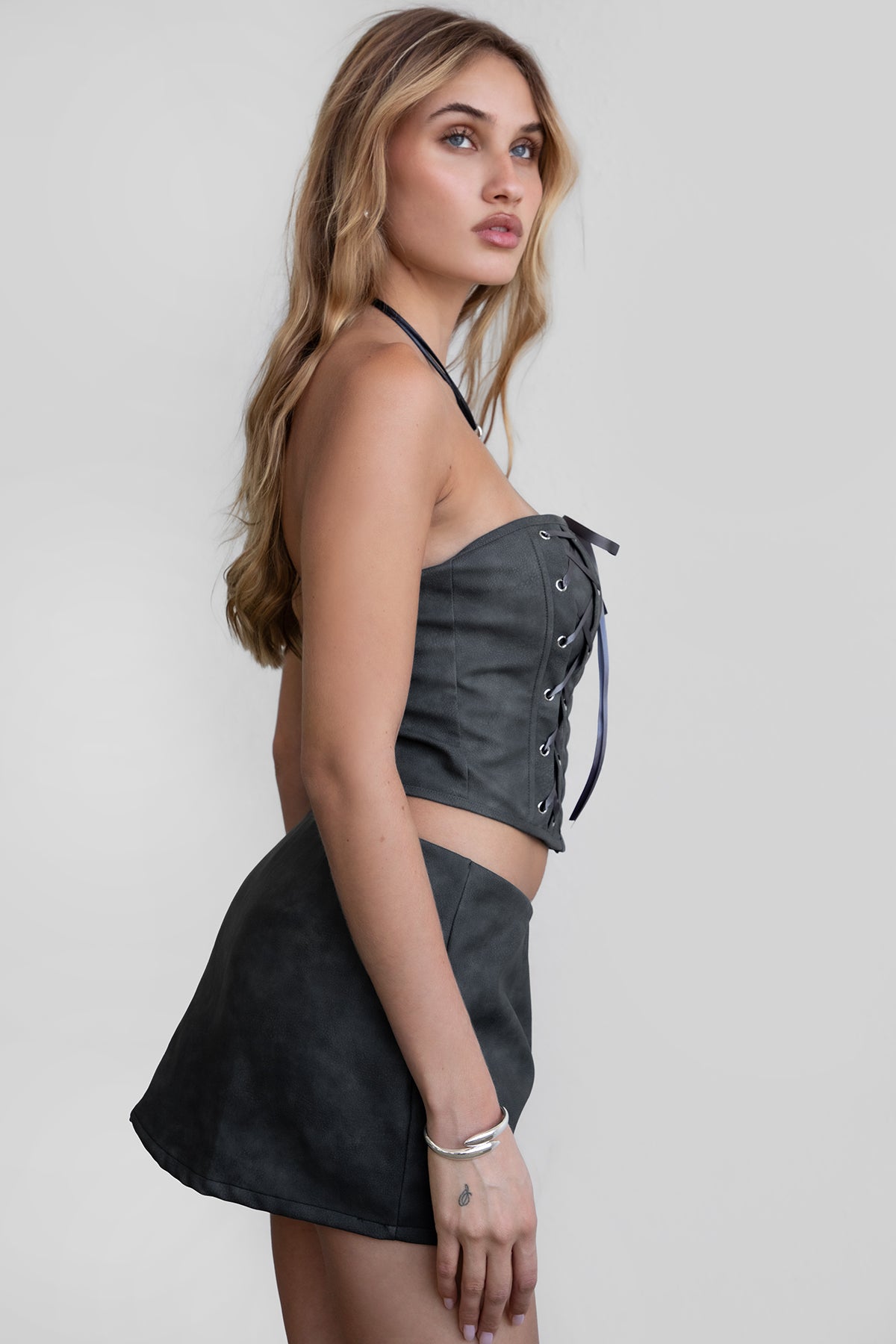 Woman wearing TIC TOC SC30492 RILEY PU vegan leather mini skirt featuring a sleek mini skort silhouette with built-in under shorts, hidden side zipper closure, and a smooth faux leather finish, styled with a matching top for an elevated going-out look.