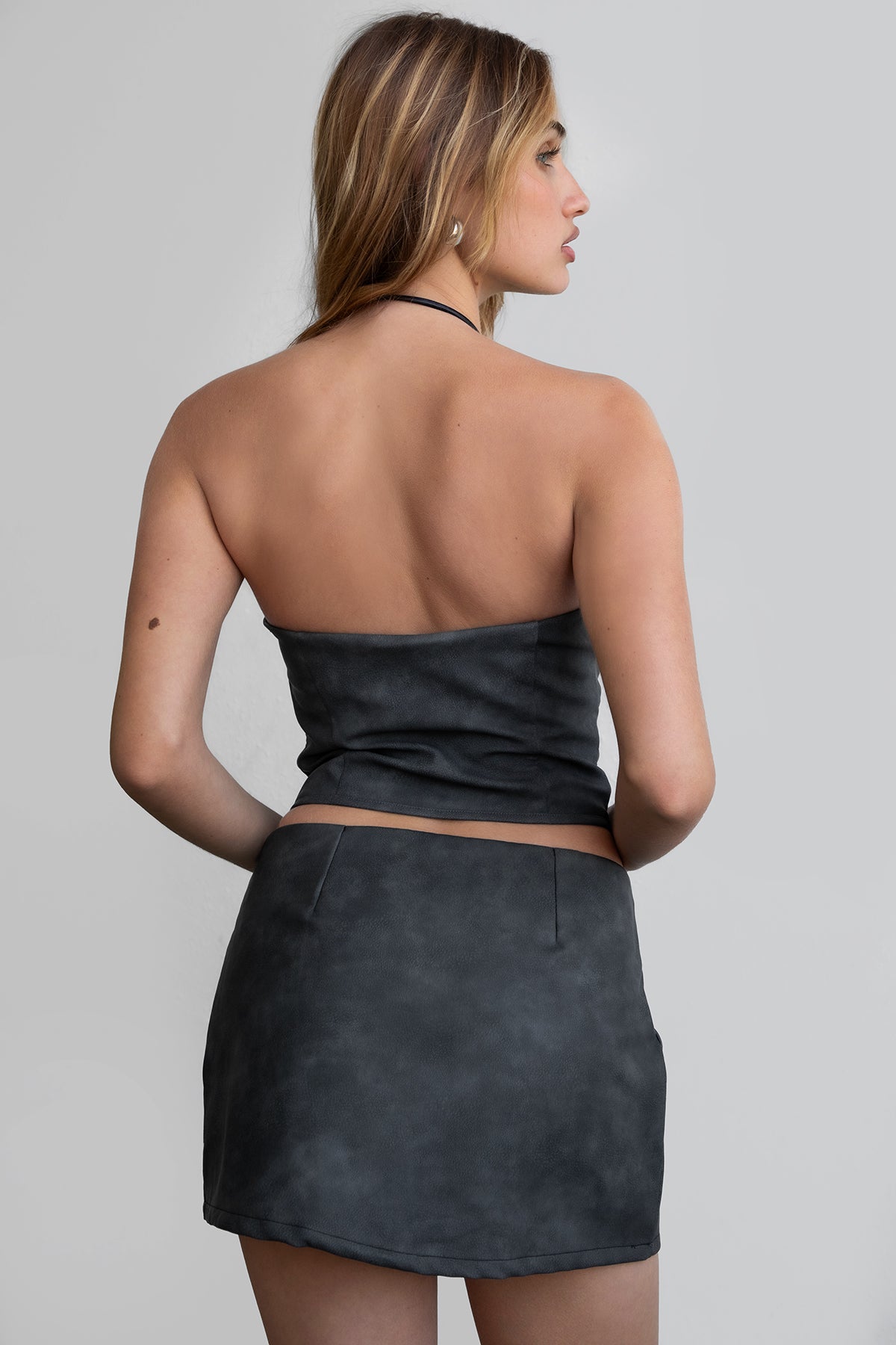 Woman wearing TIC TOC SC30492 RILEY PU vegan leather mini skirt featuring a sleek mini skort silhouette with built-in under shorts, hidden side zipper closure, and a smooth faux leather finish, styled with a matching top for an elevated going-out look.