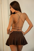 Woman wearing TIC TOC SG31603-DUSTY DUSTY western lace-up pleated skort featuring a western-inspired lace-up eyelet waistband, mid rise mini length, structured pleated denim silhouette with side zipper closure, and built-in soft inner shorts, styled with a fitted top and western boots for a festival-ready everyday western look.