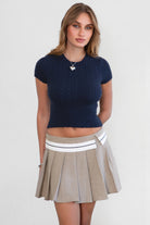 Woman wearing TIC TOC SH31098-JENS heathered twill mini skirt featuring a stone contrast waistband, crisp pleats throughout, side zipper closure, and a tailored skater silhouette for a polished preppy look.