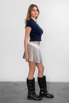 Woman wearing TIC TOC SH31098-JENS heathered twill mini skirt featuring a stone contrast waistband, crisp pleats throughout, side zipper closure, and a tailored skater silhouette for a polished preppy look.