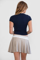 Woman wearing TIC TOC SH31098-JENS heathered twill mini skirt featuring a stone contrast waistband, crisp pleats throughout, side zipper closure, and a tailored skater silhouette for a polished preppy look.
