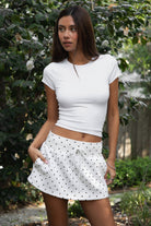 Woman wearing TIC TOC SH31896 JOTTIE plush fleece polka dot mini skort featuring an allover polka dot print, mid-rise elastic waistband with adjustable drawstring, built-in shorts, and side pockets for a cozy sporty casual look.