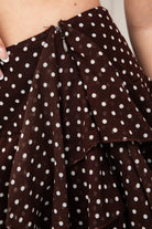 Woman wearing BISCOTTI polka dot chiffon ruffle skirt featuring a tiered mini skirt silhouette, asymmetrical dropped ruffle side detail, side zipper closure, built-in shorts lining, and a lightweight flowy hem for coquette summer and resort styling.