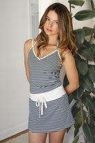 Woman wearing SAYLOR stripe stretch jersey mini skort featuring a mid rise waistband with contrast panel, adjustable waist drawstring, built-in shorts, mini skort silhouette, and soft brushed stretch jersey fabric for casual athleisure and coastal lounge styling.