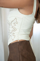 TIC TOC JESSIE Embroidered Suede Corset in Cream with square neckline, faux button front, and lace-up back.