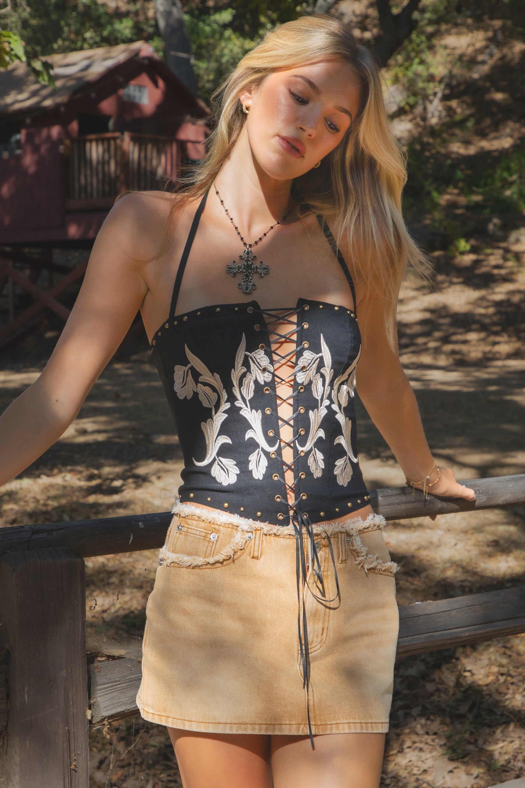 Woman wearing a black lace-up top and beige skirt outdoors