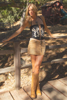 Woman in a corset and skirt standing on a wooden platform with a rustic background