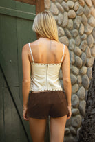 Woman wearing tic toc MAVEL Distressed PU Leather Studded Top in cream paired with suede micro shorts outdoors.