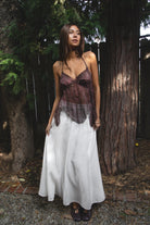 Woman wearing TIC TOC TA31758 ISOLA scalloped sequin chiffon open back halter top featuring a ruffle-trim V-neckline, delicate sequin embroidered chiffon, adjustable self-tie halter neck, open back tie closure, and a scalloped handkerchief hem, styled for a romantic vacation and elevated western evening look.