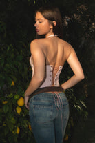 Woman wearing TIC TOC TA31791-HARTLY HARTLY halter corset top featuring a halter neck with dual back button closure, embroidered western-inspired front pattern, slim sculpted cropped fit, lace-up corset back detail, and side zipper closure, styled with high-rise jeans and heels for a romantic evening-ready look.