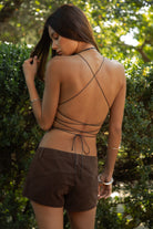 Woman wearing TIC TOC TA31793 RAVINE vegan leather halter corset top featuring a deep plunging halter neckline, western inspired embroidery detail, front lace-up corset design, sculpted waist shaping panels, and adjustable crisscross open back ties for a bold western festival look.