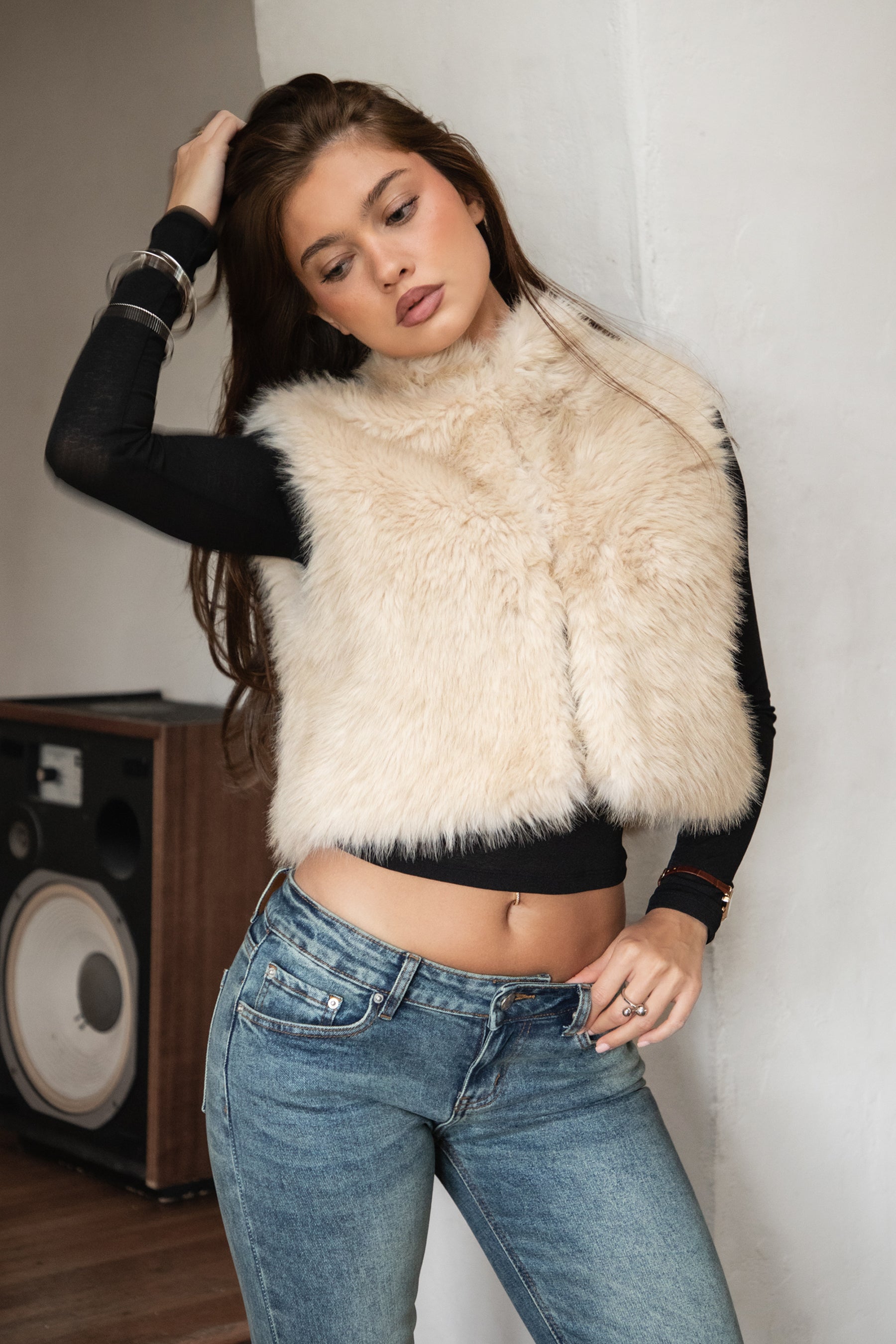 Woman wearing TIC TOC TA31834 BRIENNE faux fur vest in a natural tone; cropped open-front silhouette with plush texture, styled over a long-sleeve top and denim indoors.