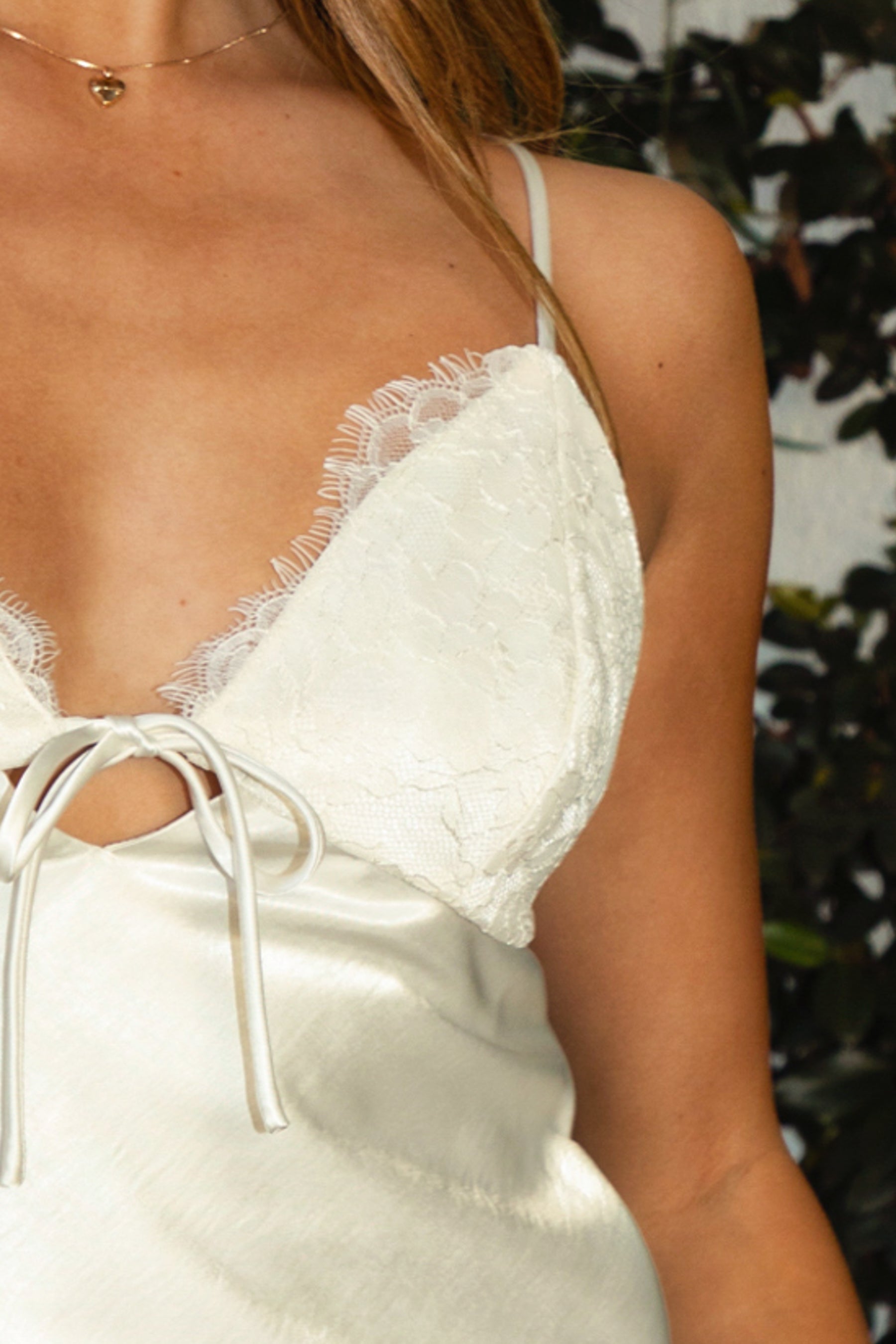 Woman wearing TIC TOC TA31926-ALORA ALORA satin lace trim front tie cropped cami top featuring a V-neckline with delicate lace trim, adjustable spaghetti straps, soft sheen satin body, front tie detail at the bust, and side zipper closure, styled with a high-waisted skirt for a feminine coquette-inspired summer evening look