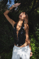 Woman wearing TIC TOC TA31927 CELESTIA matte sequin halter top featuring allover matte sequin embellishment, a deep draped cowl neckline, halter neck with adjustable strap, open back with adjustable back strap, and a relaxed flowy silhouette for a statement festival and night-out look.