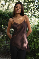 Woman wearing TIC TOC TA31968 SELINNE satin lace contrast V-neck cami top featuring smooth satin fabric, a flattering V neckline with scalloped lace trim, thin adjustable shoulder straps, and an asymmetrical lace-trim hem for a soft feminine date-night look.