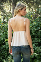 Woman wearing SOIE split V-neck satin cami top featuring scalloped lace trim along the neckline and front panel, adjustable self tie shoulder straps, five button front closure, front split hem detail, and an elastic back band for a soft feminine silhouette.