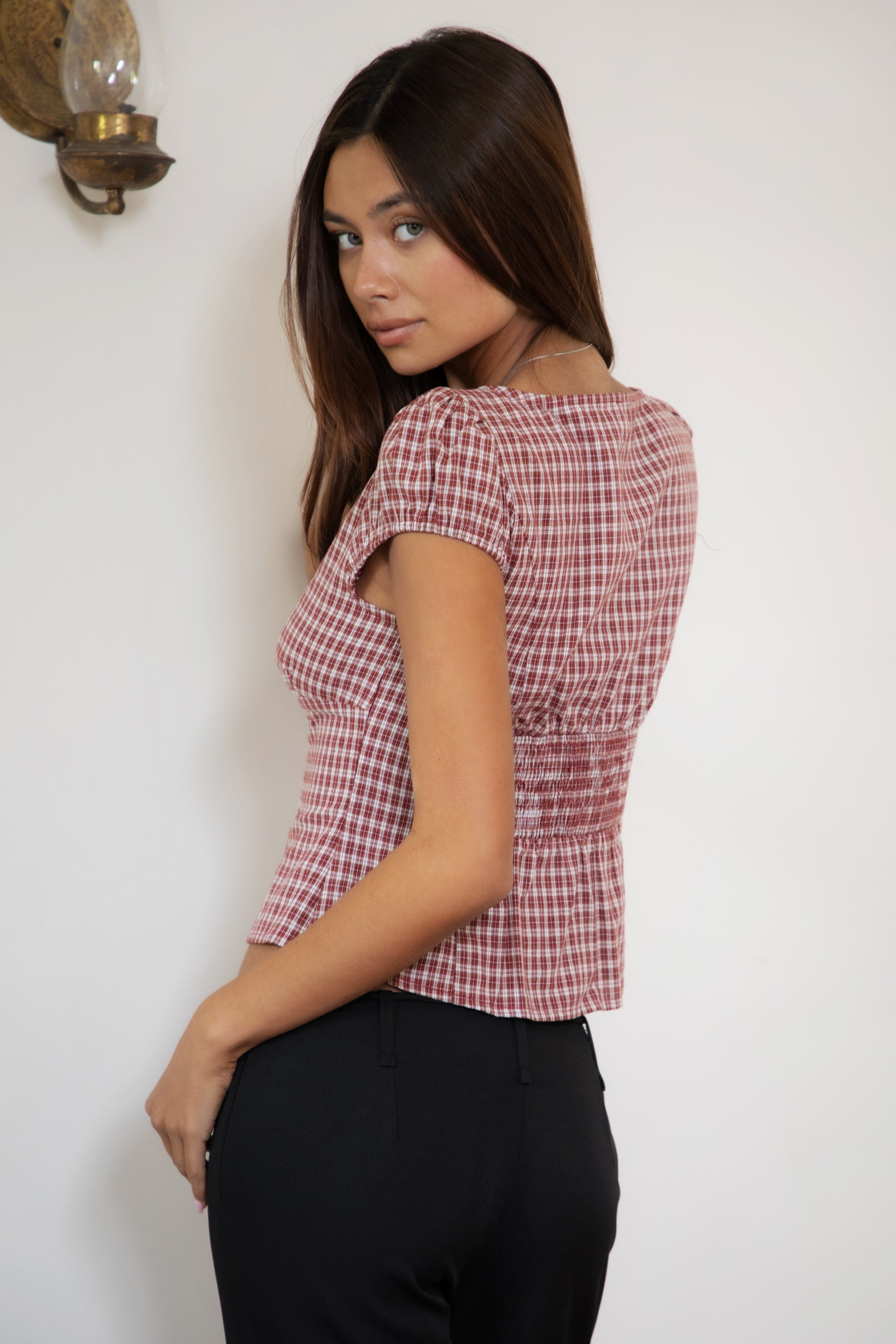 Woman wearing TIC TOC TA32072 DARIS gingham puff sleeve blouse top featuring soft cotton gingham fabric with a classic check pattern, cropped feminine fit, round neckline with front button closure, puff short sleeves, smocked back panel, and under bust smocking for a vintage-inspired western look.