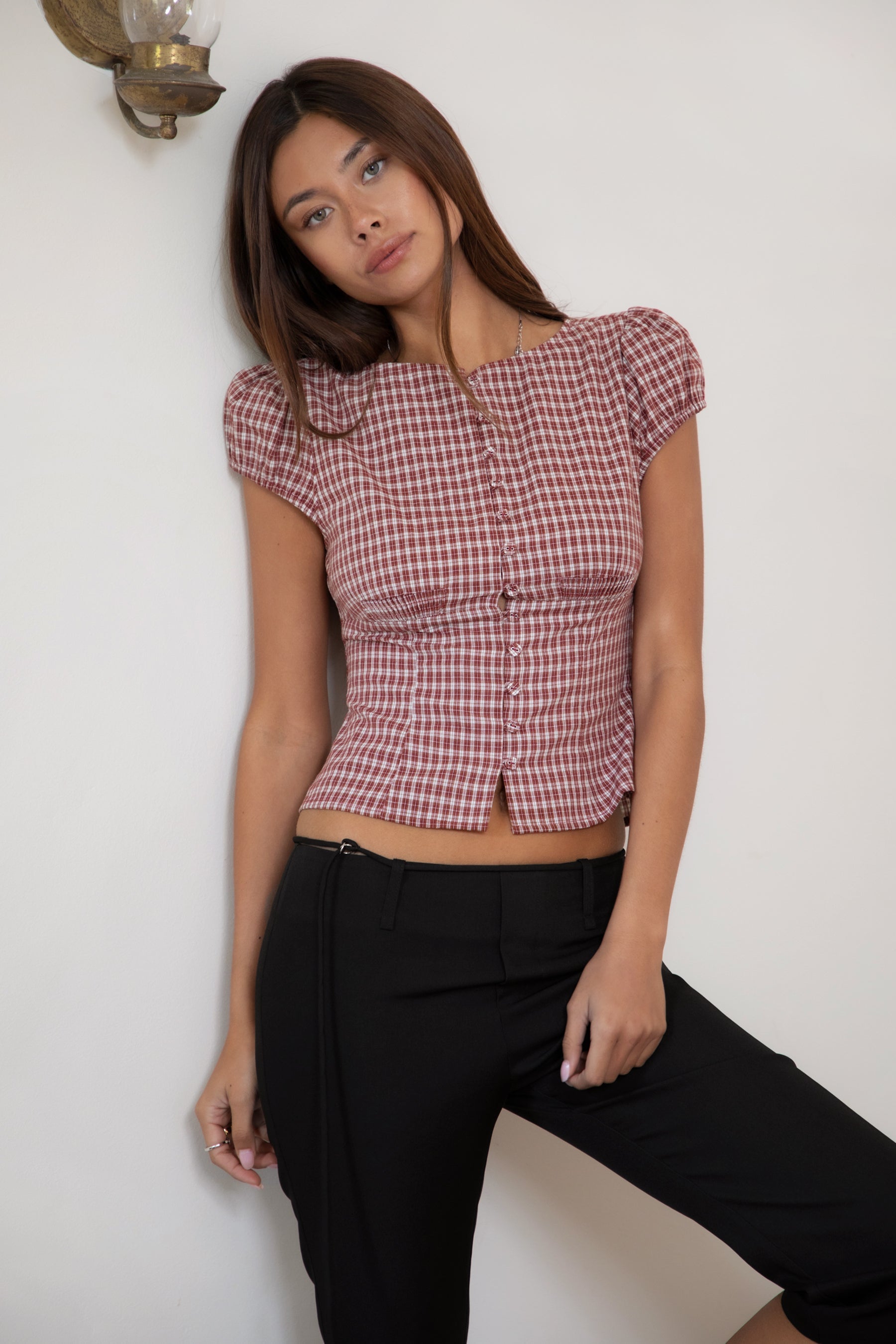 Woman wearing TIC TOC TA32072 DARIS gingham puff sleeve blouse top featuring soft cotton gingham fabric with a classic check pattern, cropped feminine fit, round neckline with front button closure, puff short sleeves, smocked back panel, and under bust smocking for a vintage-inspired western look.