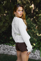 Woman wearing LACEWOOD polka dot chiffon lace long sleeve blouse top featuring sheer dotted chiffon fabric, scalloped lace trim along the V-neckline and cuffs, floral lace panel under the bust, flowy silhouette with flare hem, and front button closure for adjustable styling
