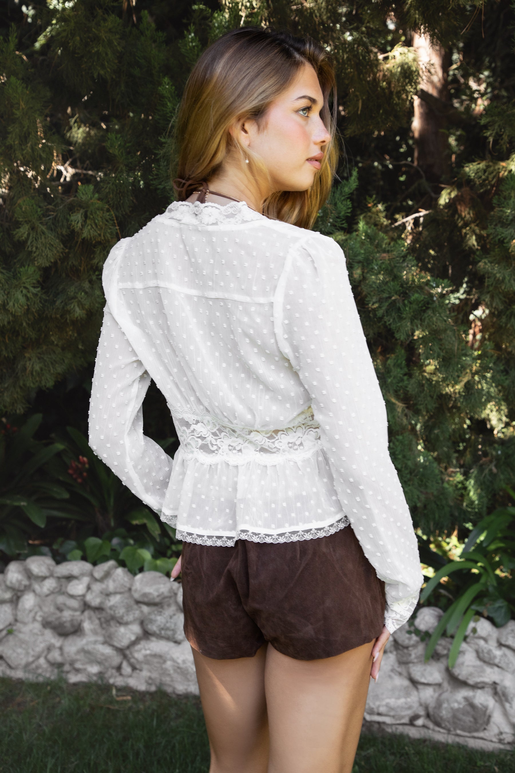 Woman wearing LACEWOOD polka dot chiffon lace long sleeve blouse top featuring sheer dotted chiffon fabric, scalloped lace trim along the V-neckline and cuffs, floral lace panel under the bust, flowy silhouette with flare hem, and front button closure for adjustable styling