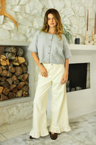 Woman wearing HOLLIS roll neck drop shoulder short sleeve knit sweater featuring a minimal rolled neckline, relaxed semi oversized silhouette, short sleeves with rolled cuffs, ribbed hem, front marbled button closure, and lightweight cotton knit for everyday layering.